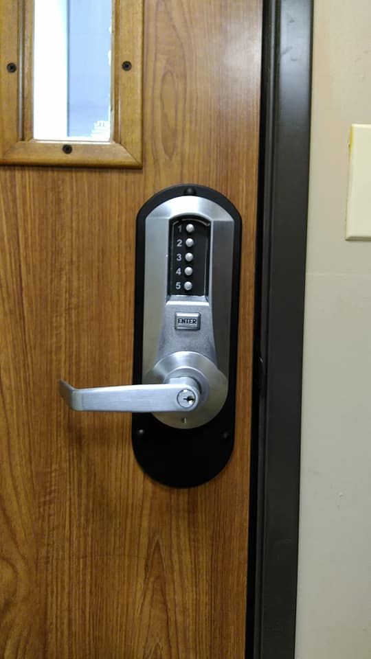 A wood-grain door with a metal lever handle and a digital keypad lock for access control.
