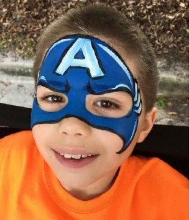 Boy with blue Captain America face paint smiling.