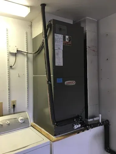A large air conditioner is sitting in a laundry room next to a washer and dryer.