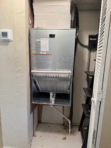 An air conditioner is installed in a closet next to a wall.