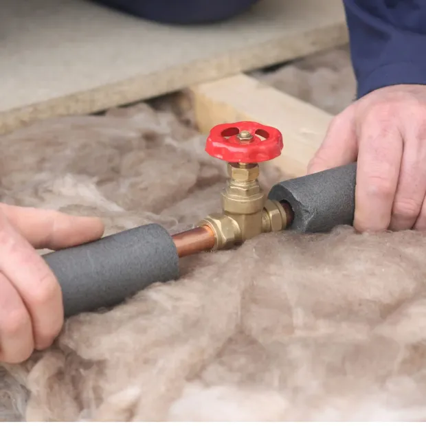 A person is working on a pipe with a red valve