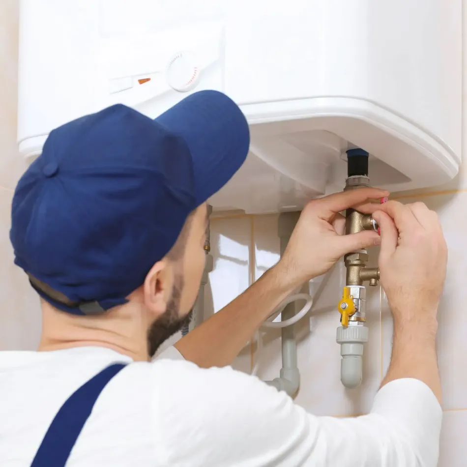 A man in a blue hat is fixing a water heater