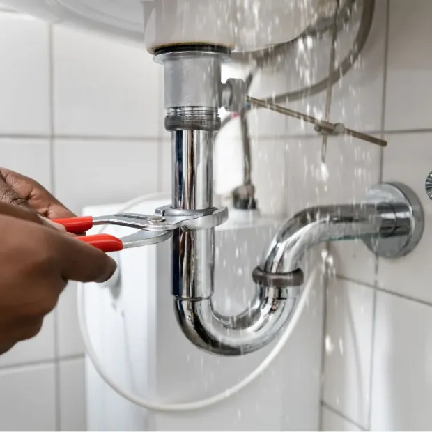 A person is fixing a sink pipe with a wrench.