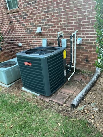 An air conditioner is sitting on the side of a brick building.