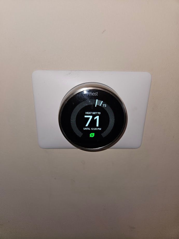 A smart thermostat is mounted on a wall.