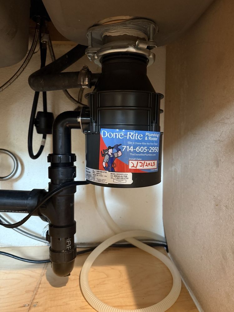 close-up of garbage disposal unit installation and drain piping under kitchen sink in Orange CA