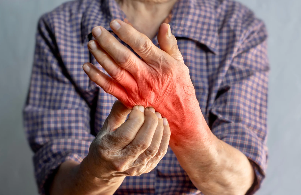 An elderly woman is holding her wrist in pain.