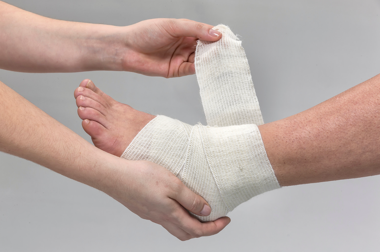 A person is bandaging another person 's ankle with a bandage.