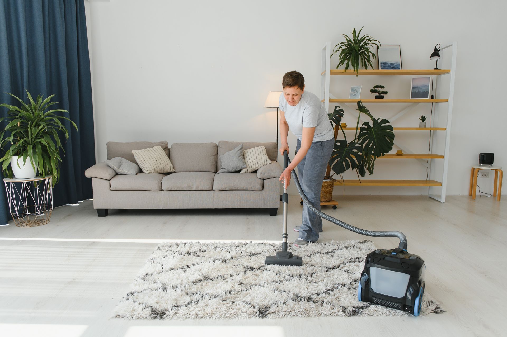 A man is vacuuming a rug in a living room.