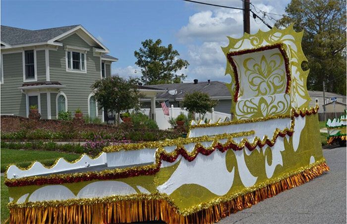 Parade float decorated in gold and white, on a residential street.