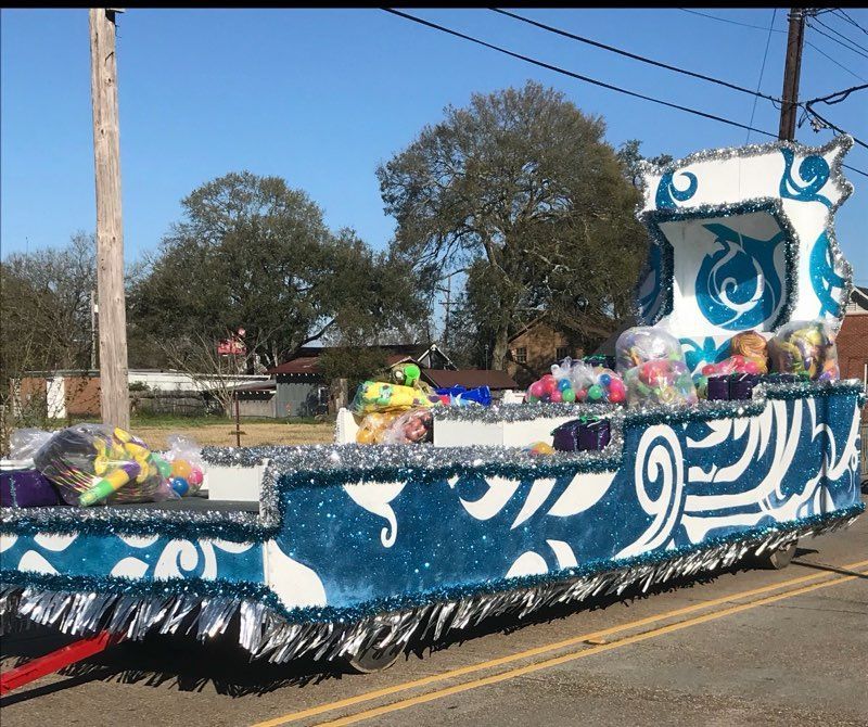 A decorated parade float with blue and silver trim, filled with wrapped gifts, in an outdoor setting.