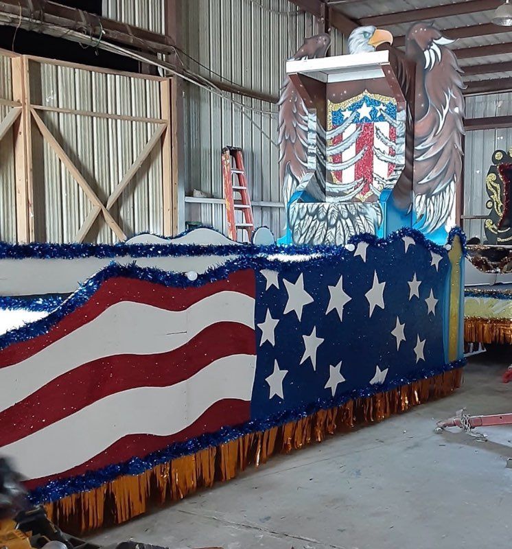 Patriotic float with a large eagle, American flag design, blue and red with gold fringe.