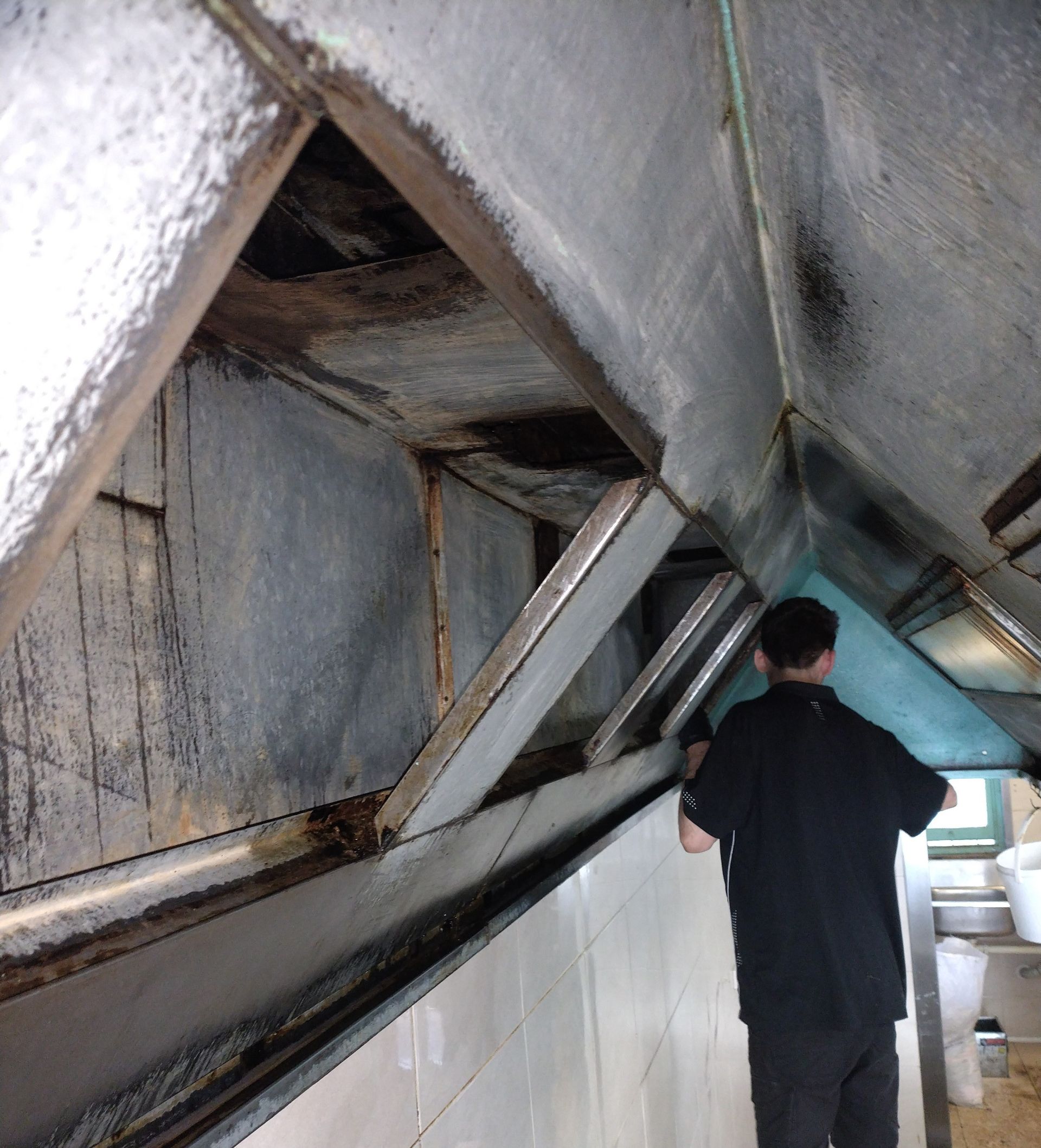 Person Inspects a Grimy Commercial Kitchen Exhaust Hood — Central Coast Commercial Kitchen Cleaning in Woy Woy, NSW