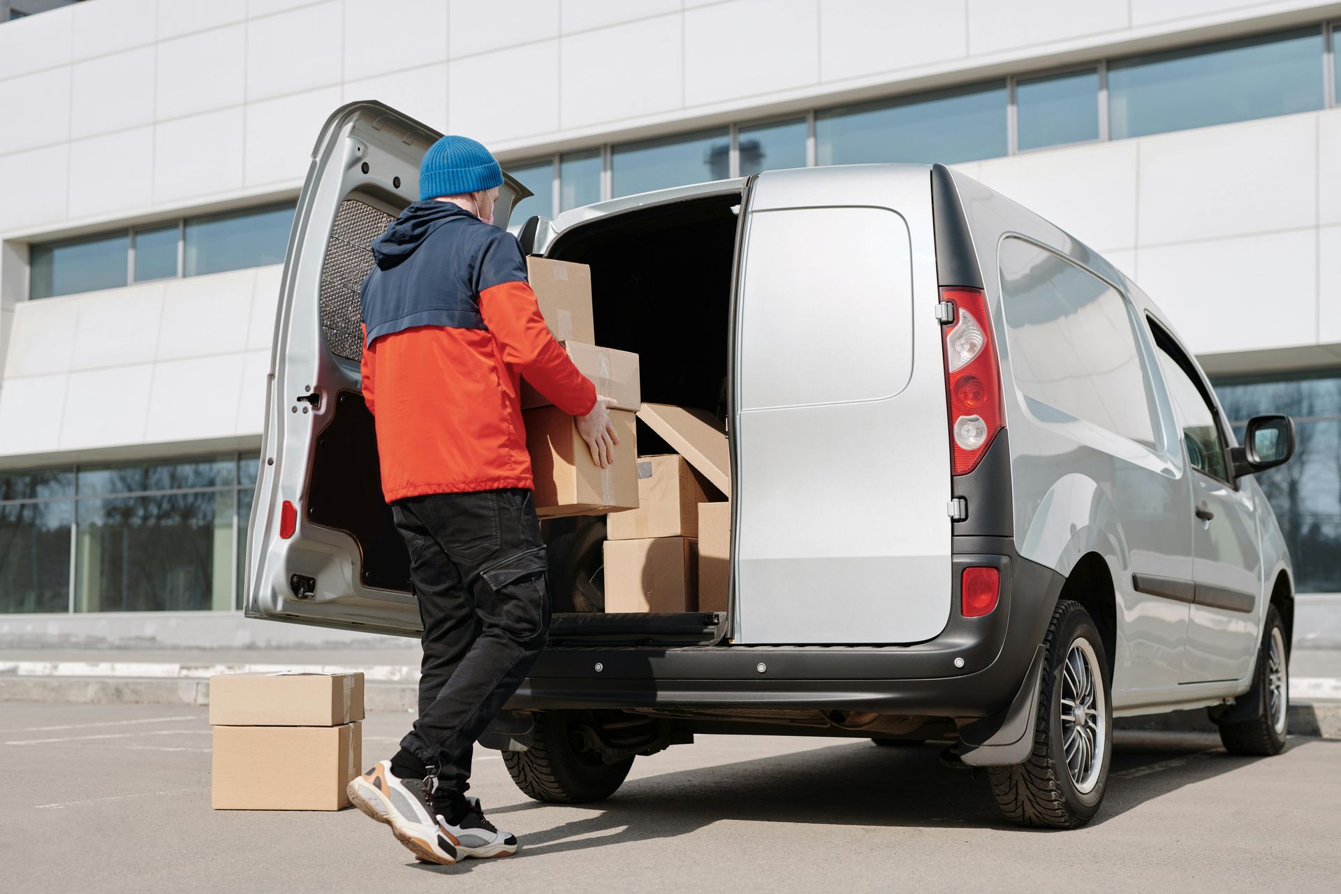 A delivery man is loading boxes into the back of a van.