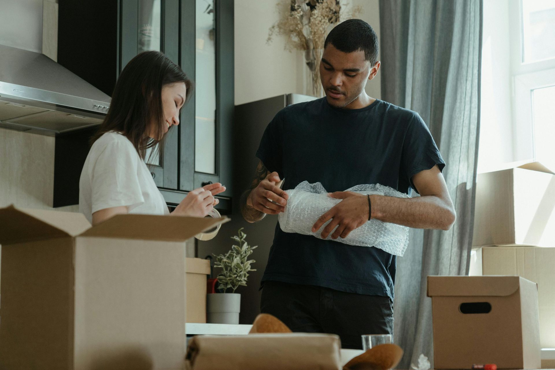 A man and a woman are packing boxes in a kitchen.