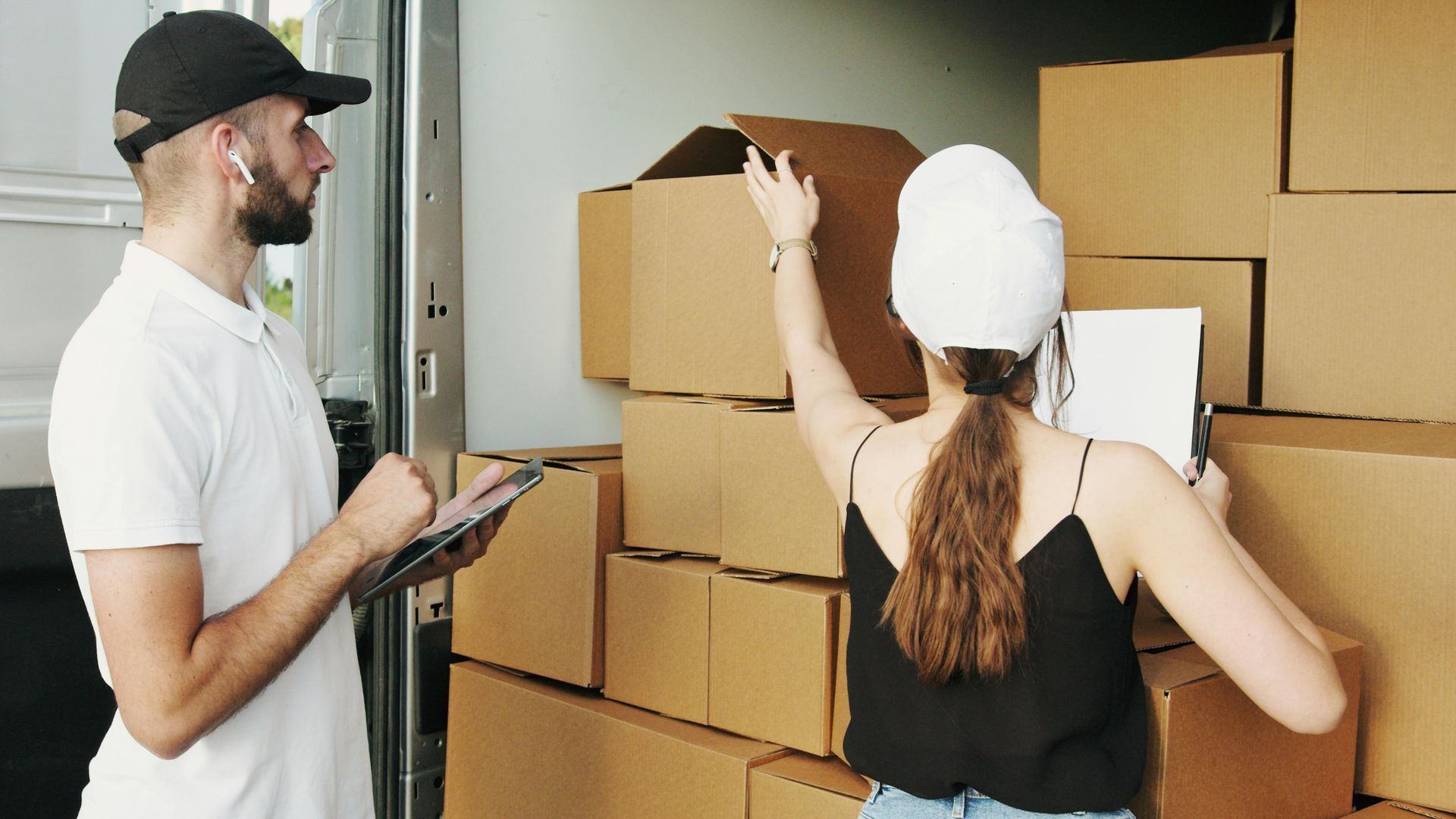 A man and a woman are standing in front of a stack of cardboard boxes.