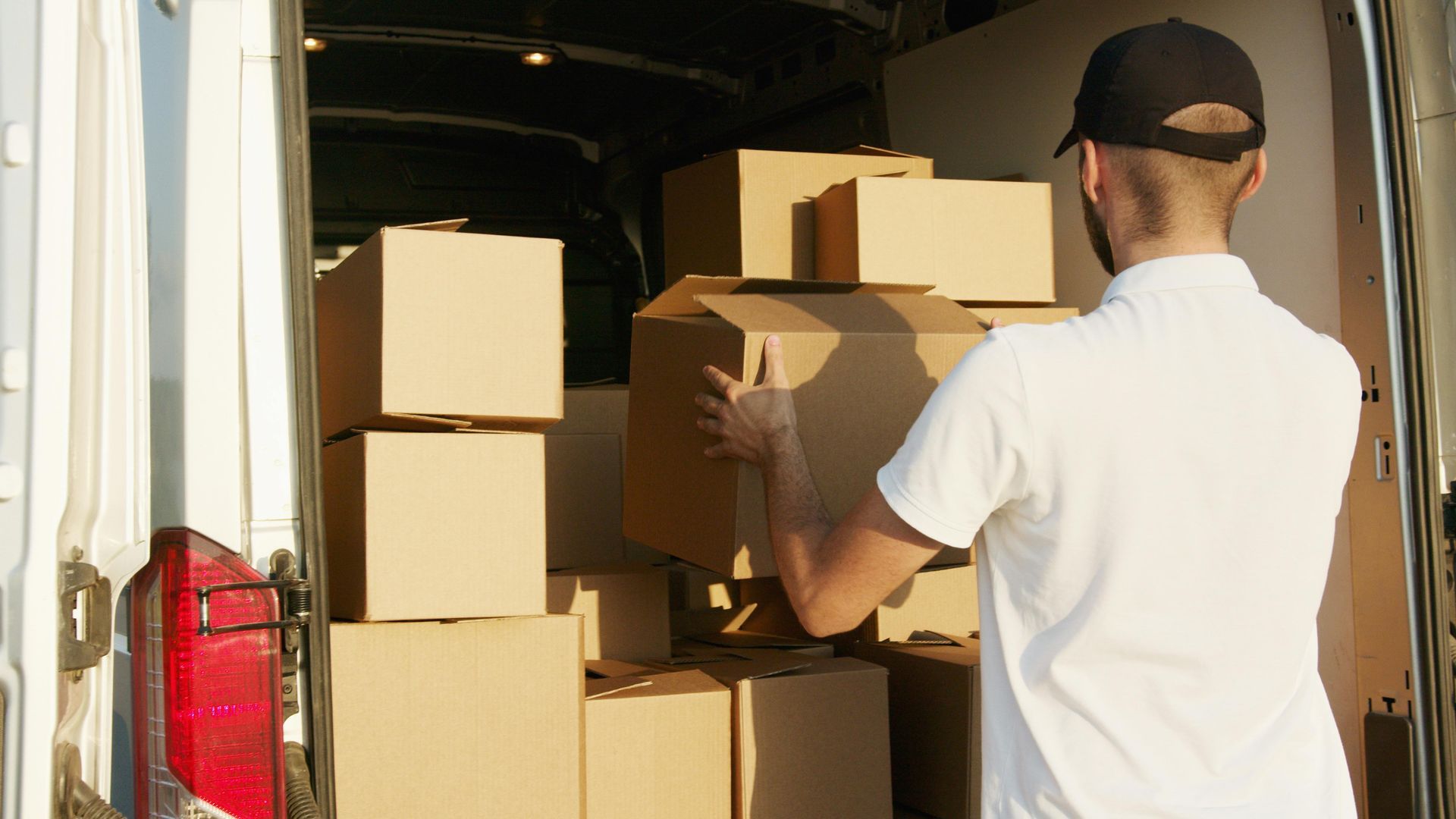 A delivery man is loading boxes into a van.