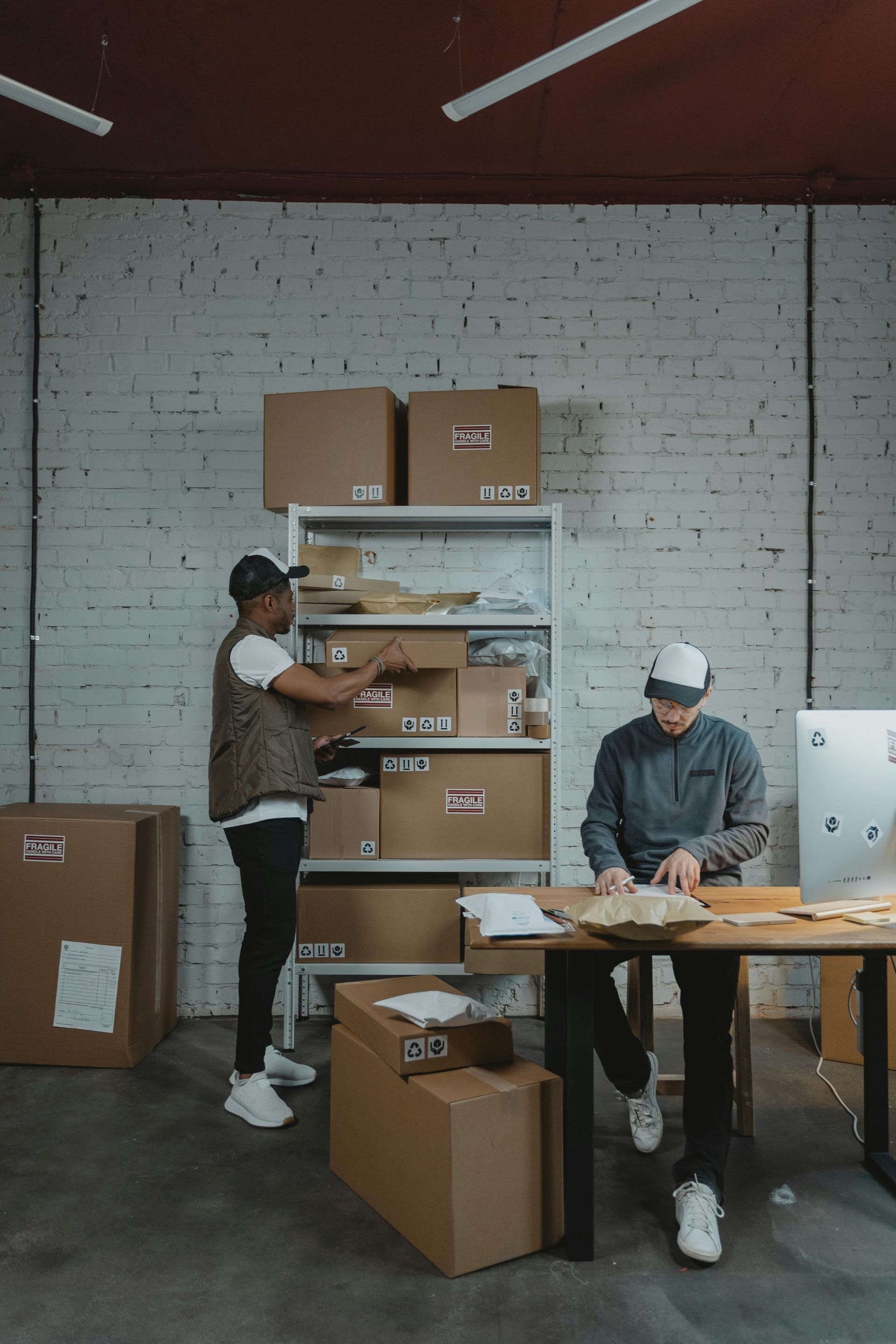 Two men are working in a warehouse filled with boxes.