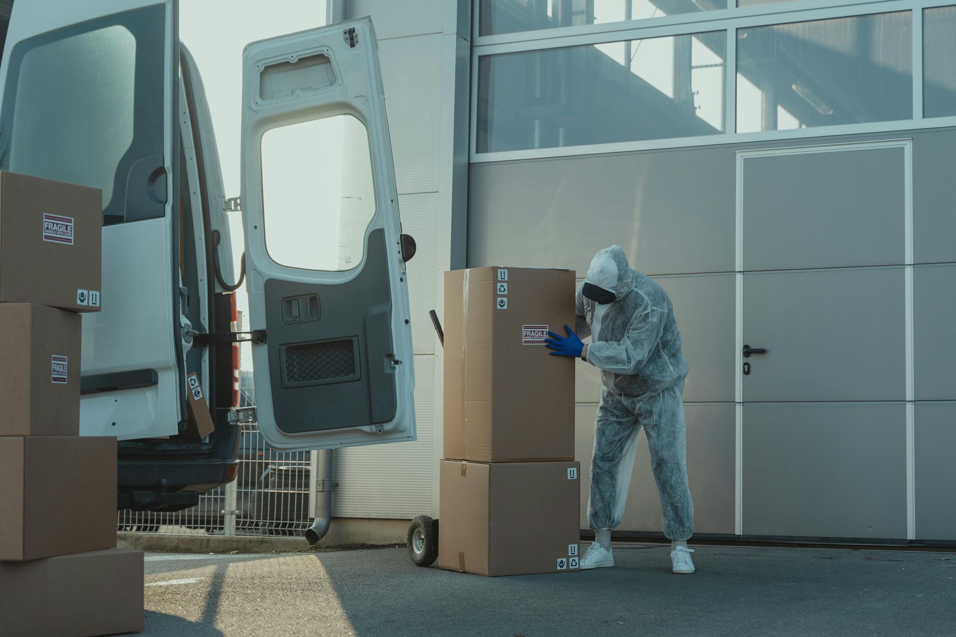 A man in a protective suit is loading boxes into a van.