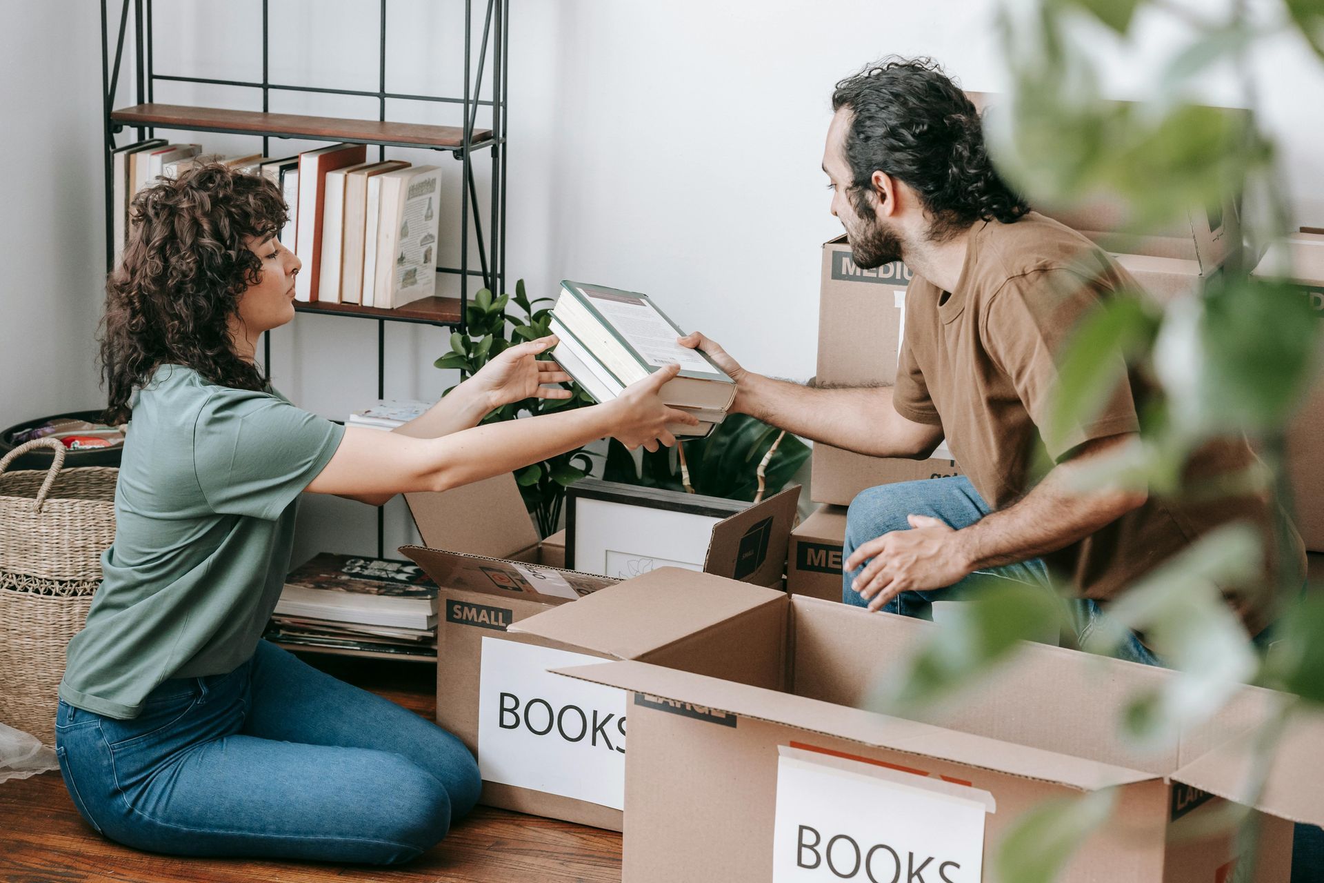 A man and a woman are sitting on the floor holding books.