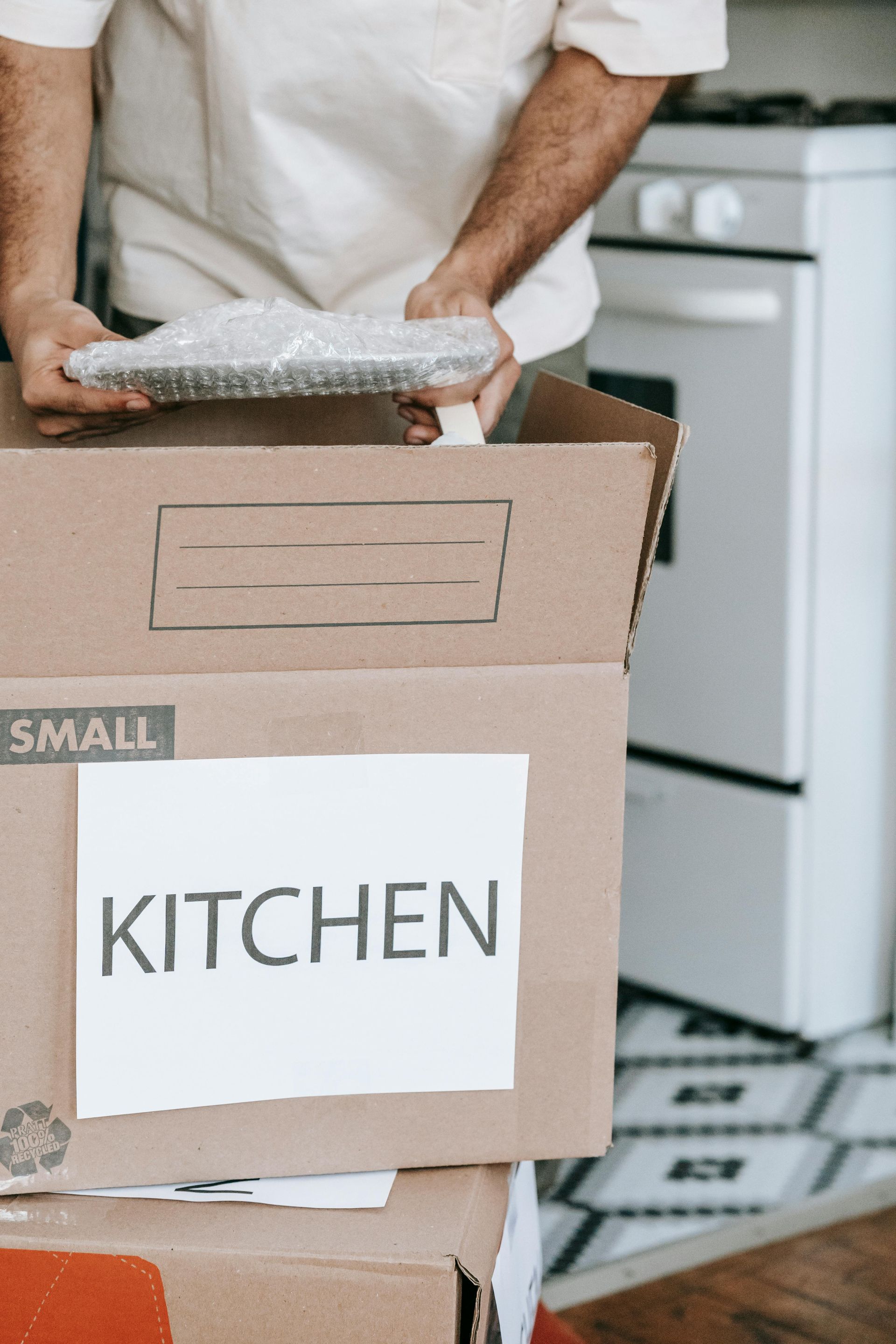 A man is holding a box that says kitchen on it.