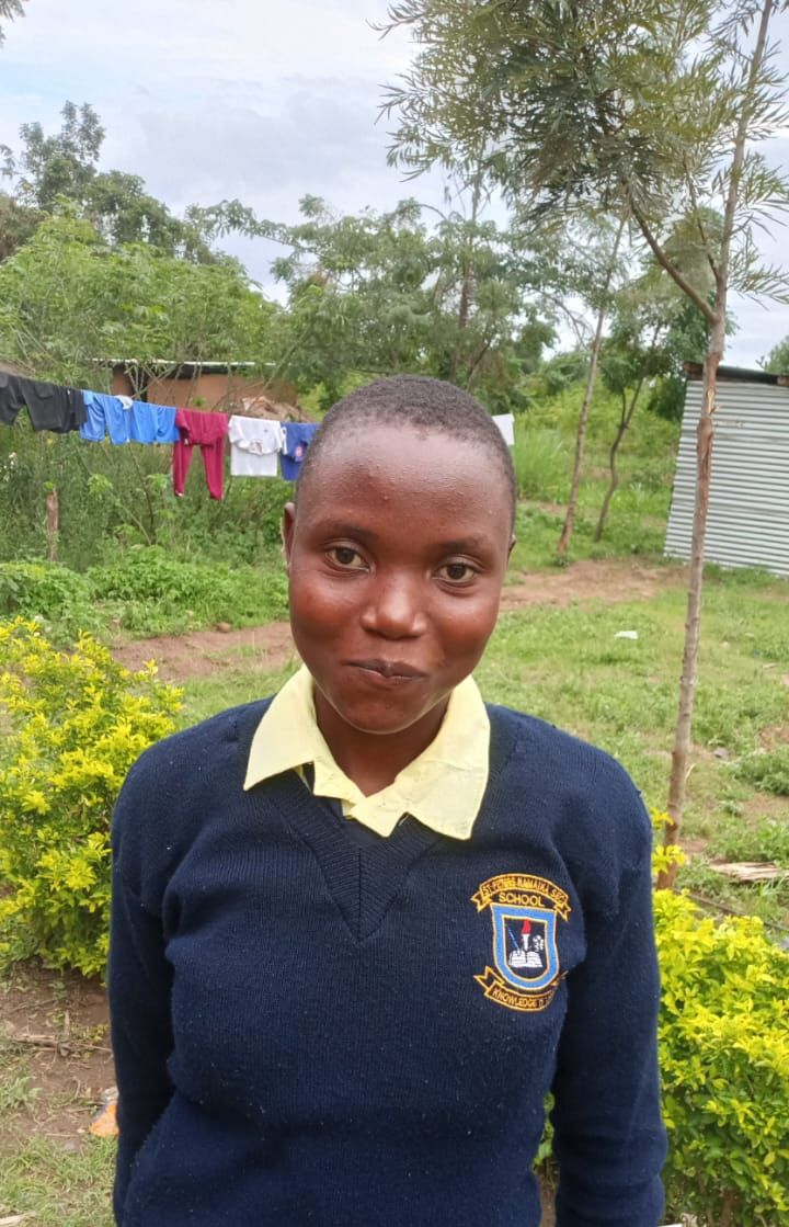 Young Black man in white shirt, looking at camera, in room with beds.