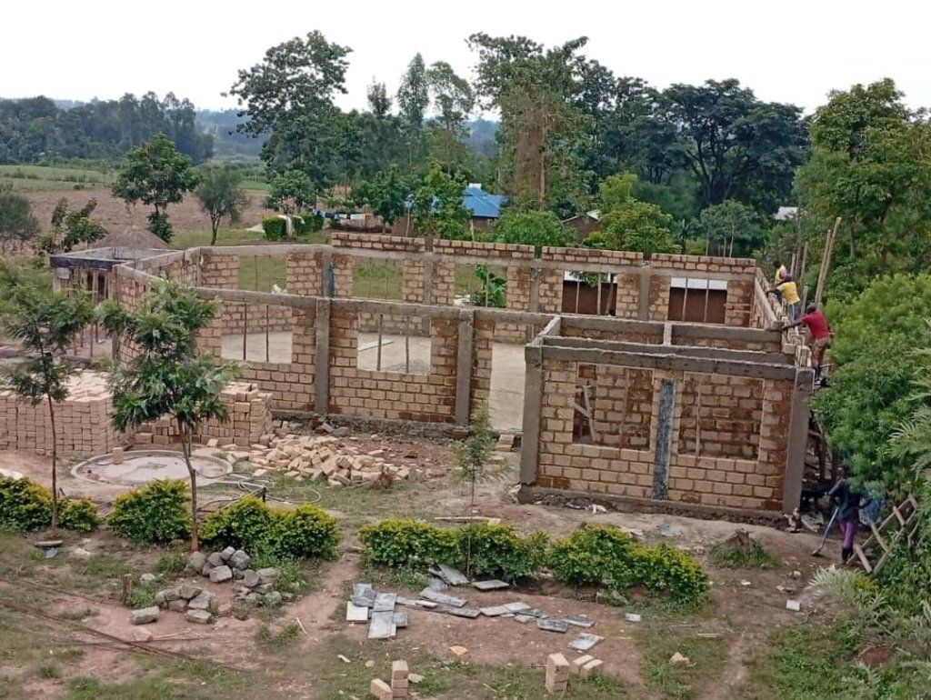 Building under construction in a rural setting, with brick walls and open windows.