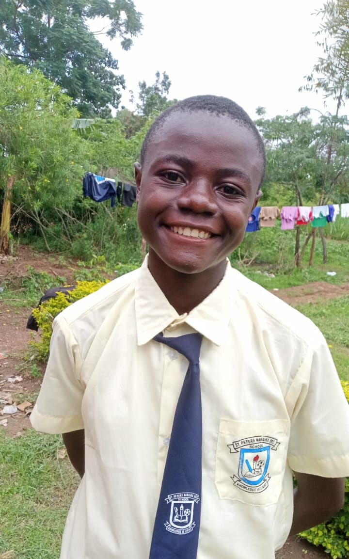 Young child in blue shirt, outdoors, looking at the camera.