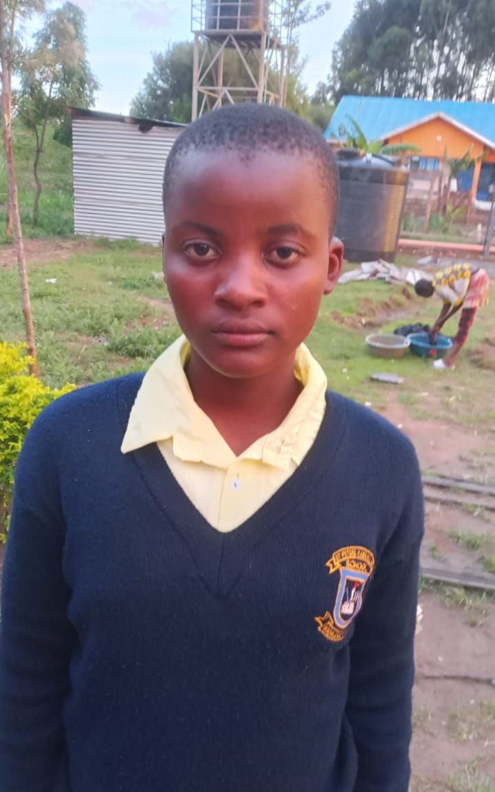 Young Black man in white shirt, looking at camera, in room with beds.