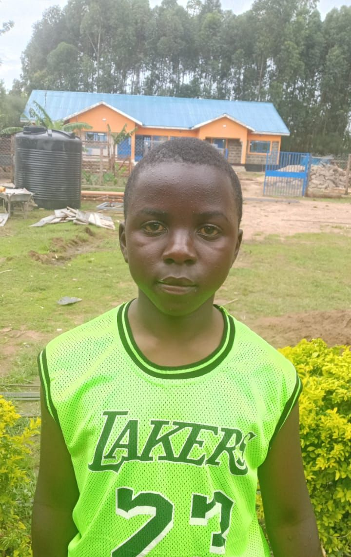 Man with a shaved head in a lime green hoodie; outside a building, sunny day.