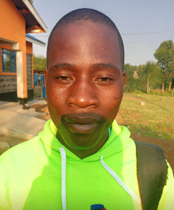 Man with a shaved head in a lime green hoodie; outside a building, sunny day.