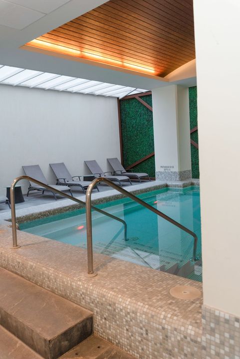Piscina cubierta con tumbonas, escalones de azulejos y pared verde.