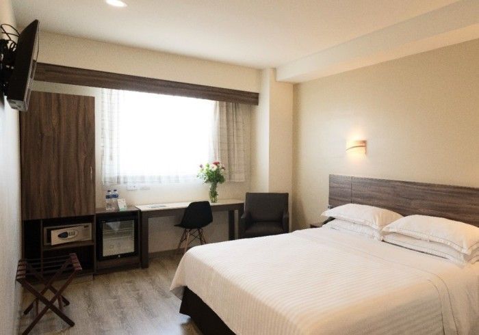 Habitación de hotel con cama, escritorio, silla y ventana.