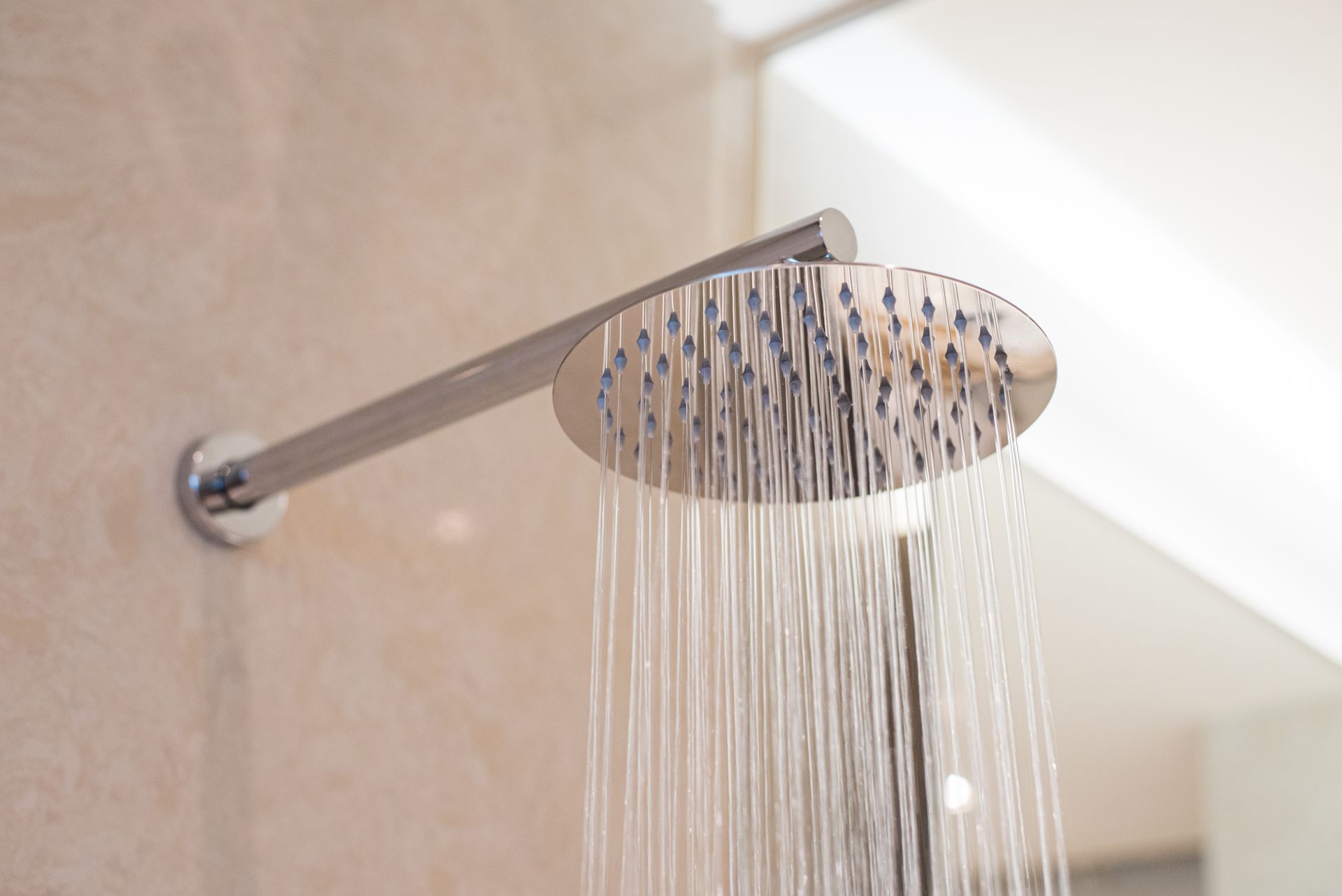 A close up of a shower head in a bathroom with water coming out of it.