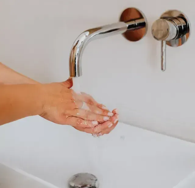A person is washing their hands in a bathroom sink.