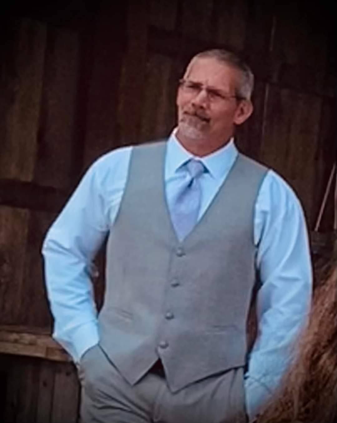 A man in a suit and tie is standing with his hands in his pockets.