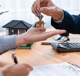 A man is giving a house key to another man.