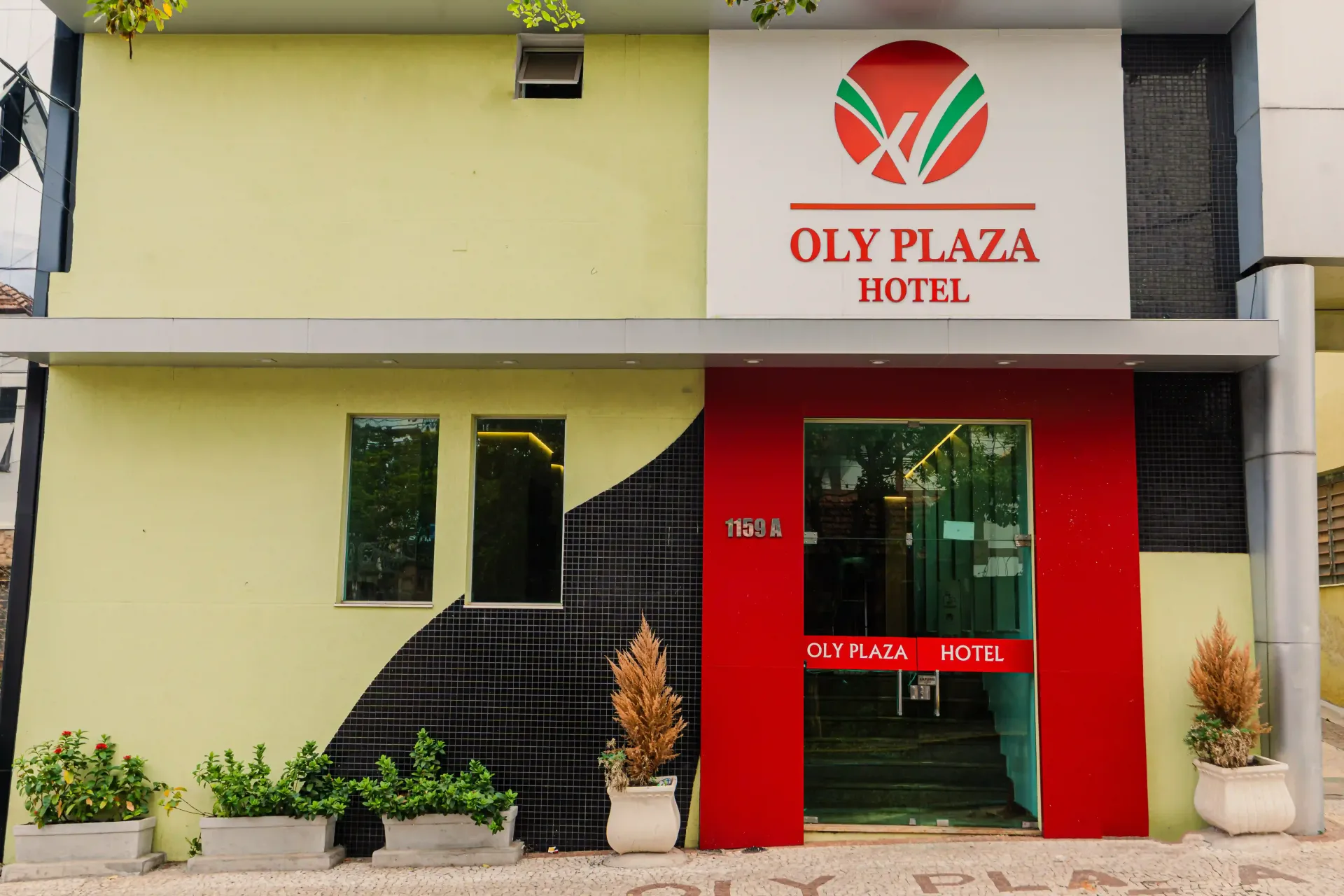 Um prédio amarelo com uma placa que diz oly plaza hotel Oly Plaza Hotel