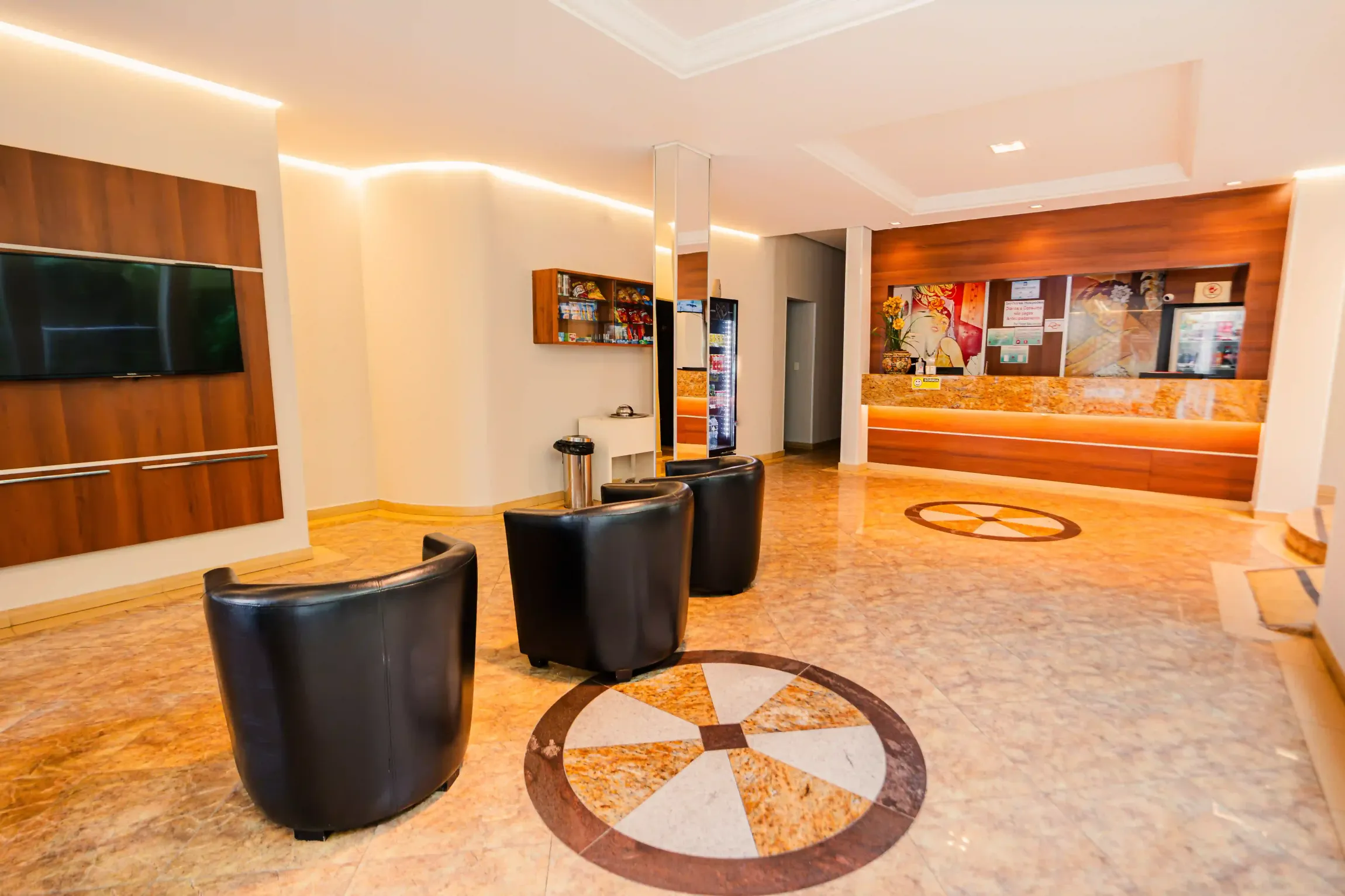 Um lobby de hotel com cadeiras e uma televisão Oly Plaza Hotel