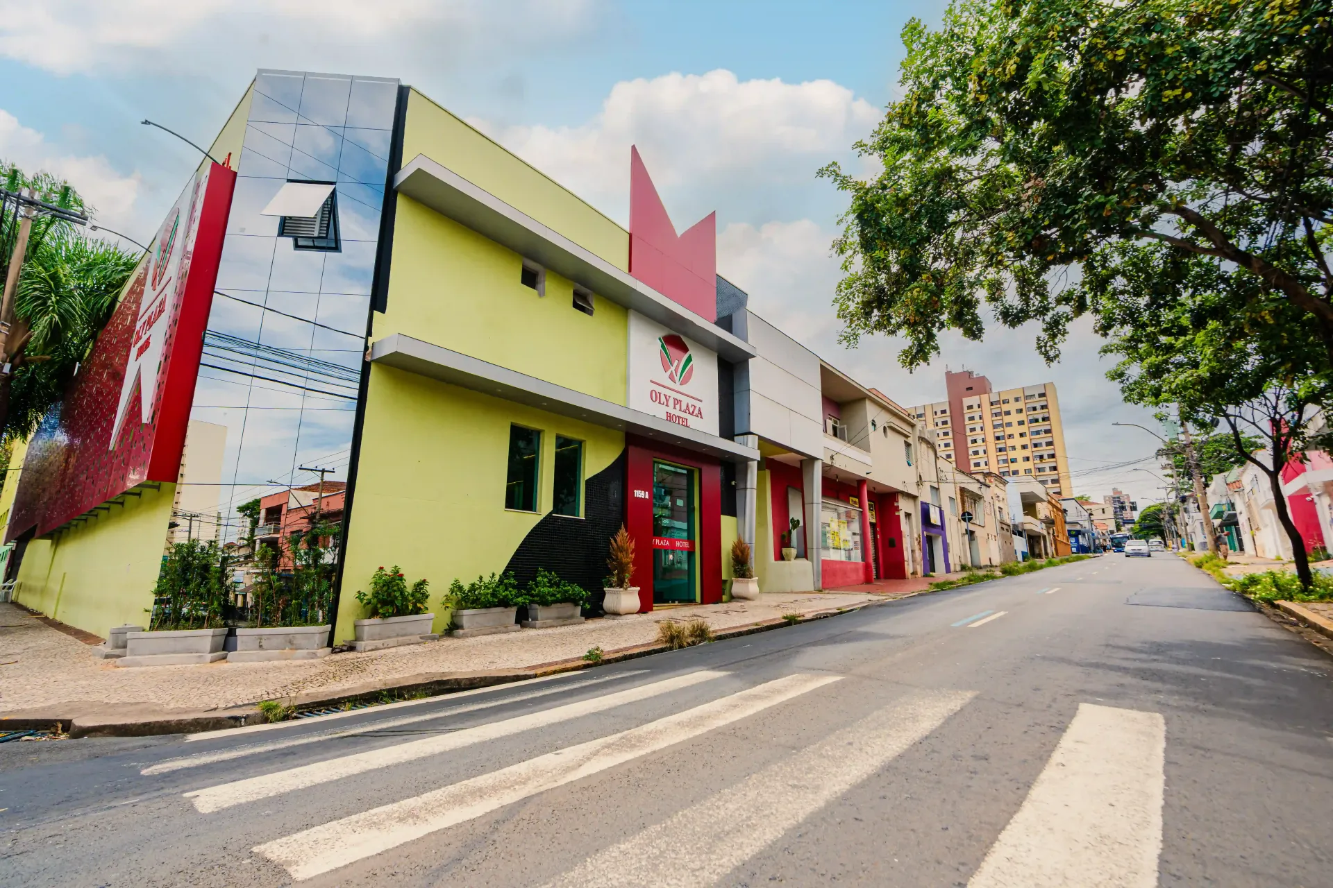 Um prédio amarelo e vermelho com a letra f nele Oly Plaza Hotel