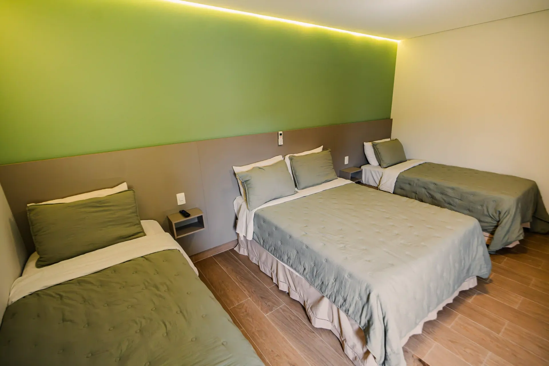 Um quarto de hotel com três camas e uma parede verde Oly Plaza Hotel