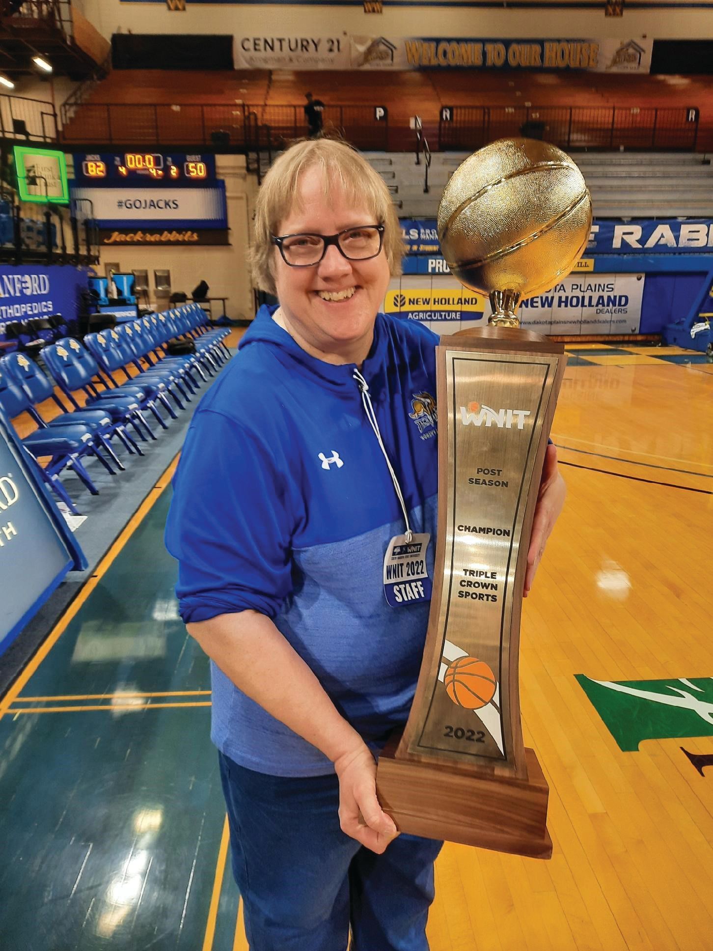 Photo of Sonja Anderson holding the WNIT trophy in Frost Arena.