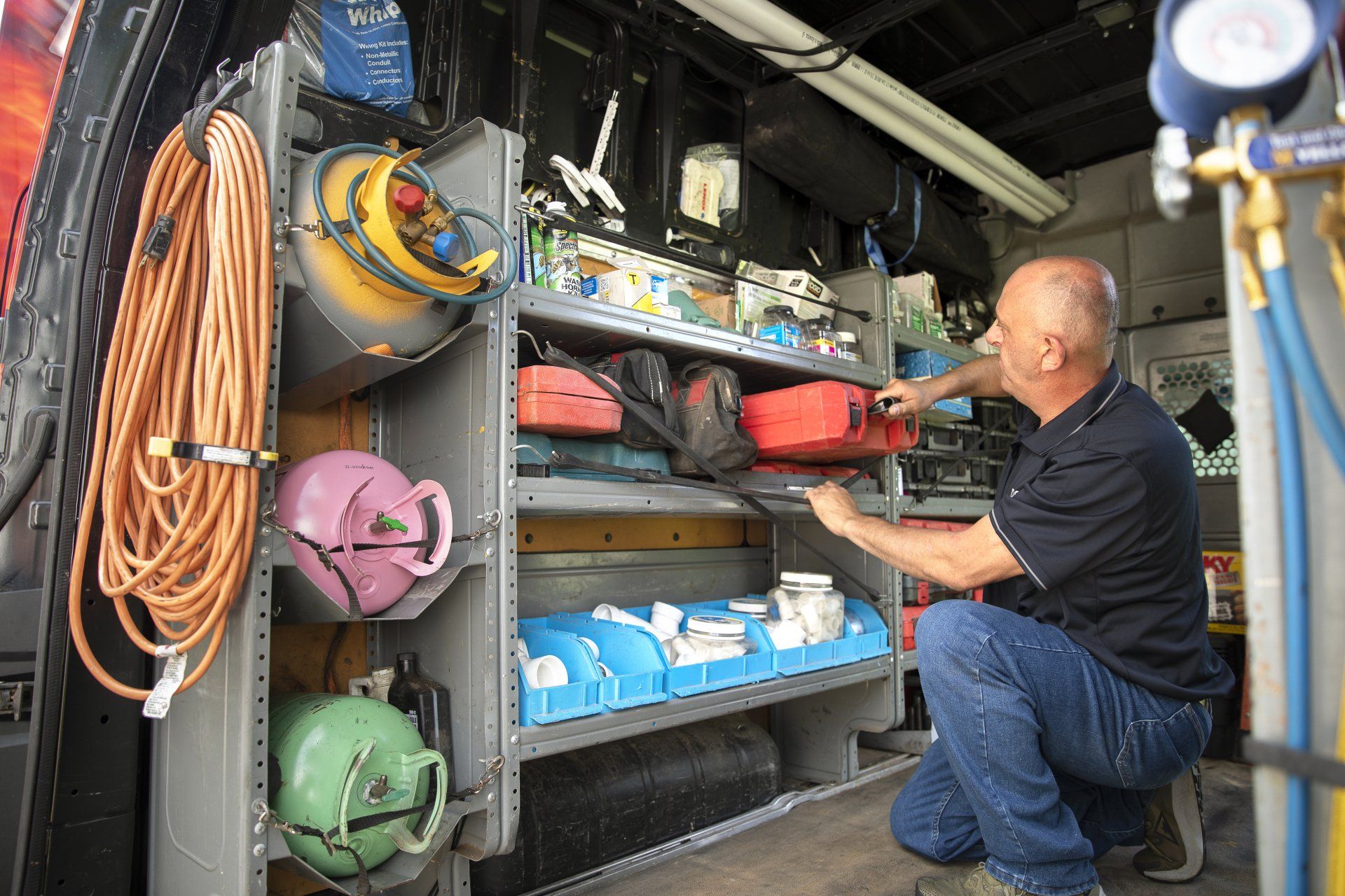 A man is kneeling in the back of a Dolce HVAC van.