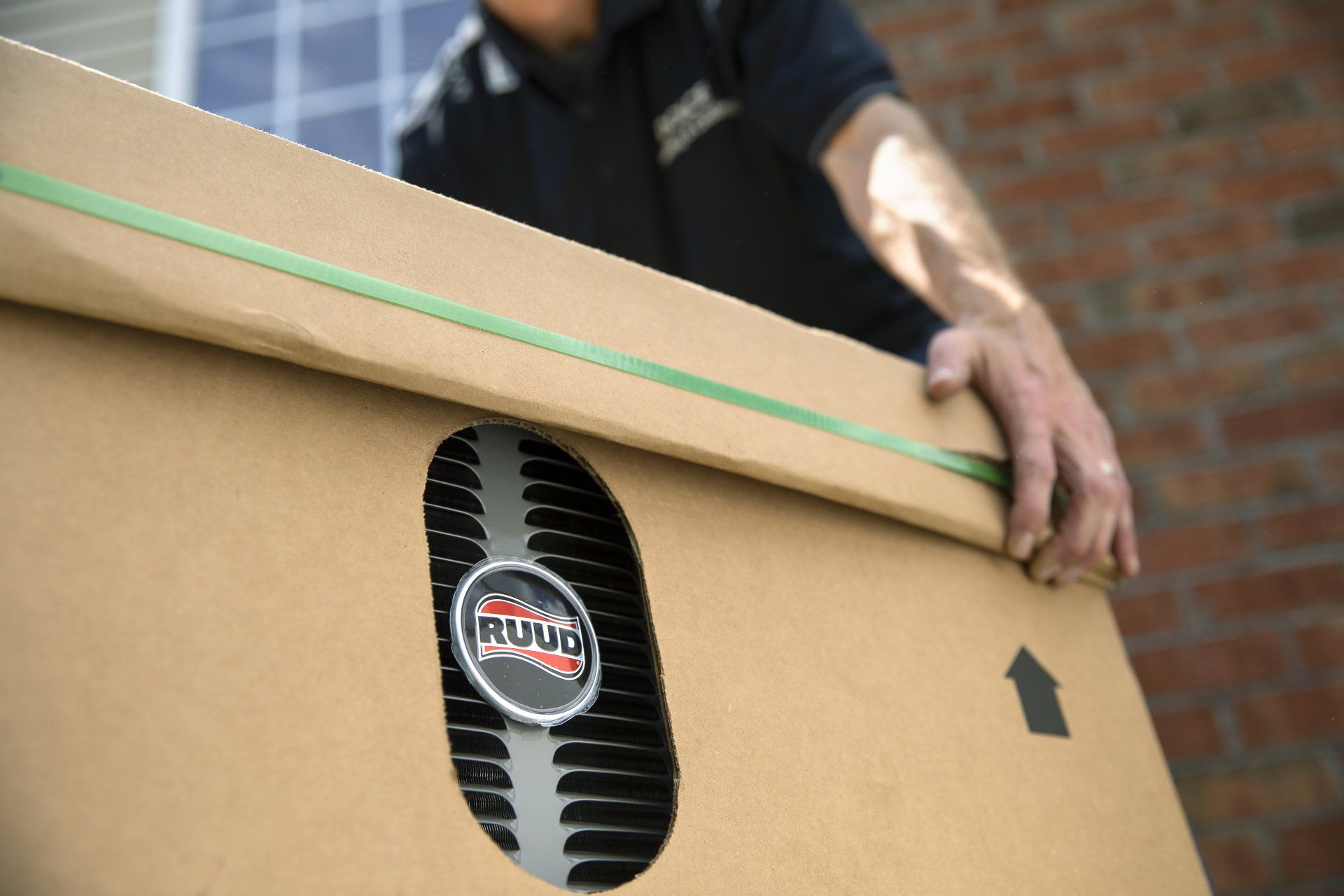 A man is holding a cardboard box with a logo on it that says Ruud