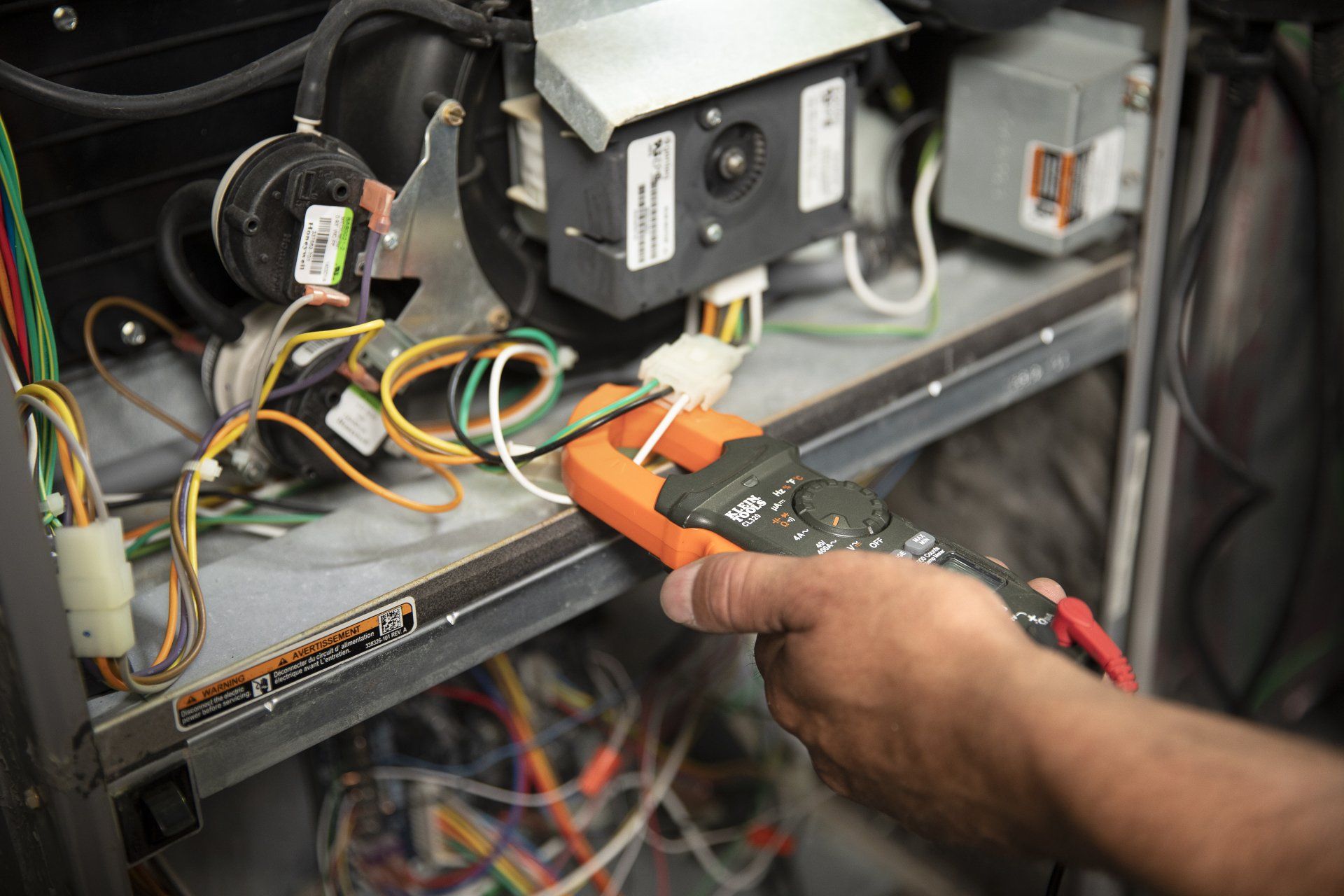 A person is using a digital multimeter to test a machine.