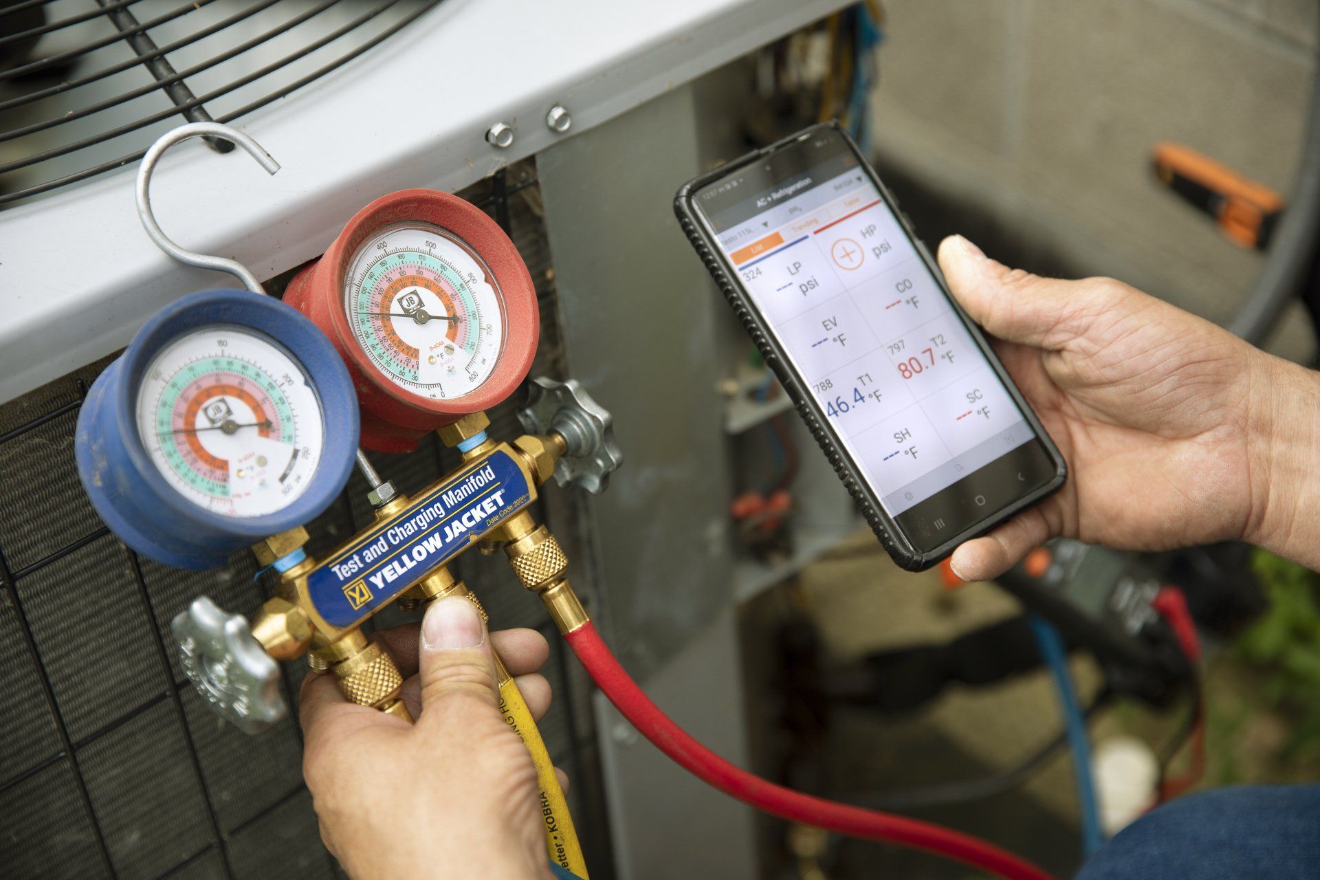 A person is holding a cell phone next to a pair of gauges.