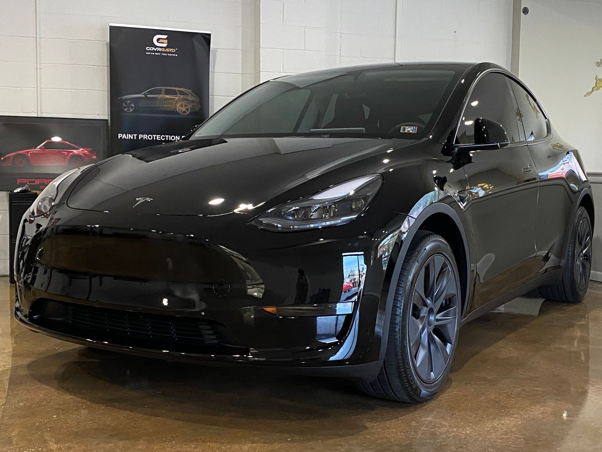 A black tesla model y is parked in a showroom.