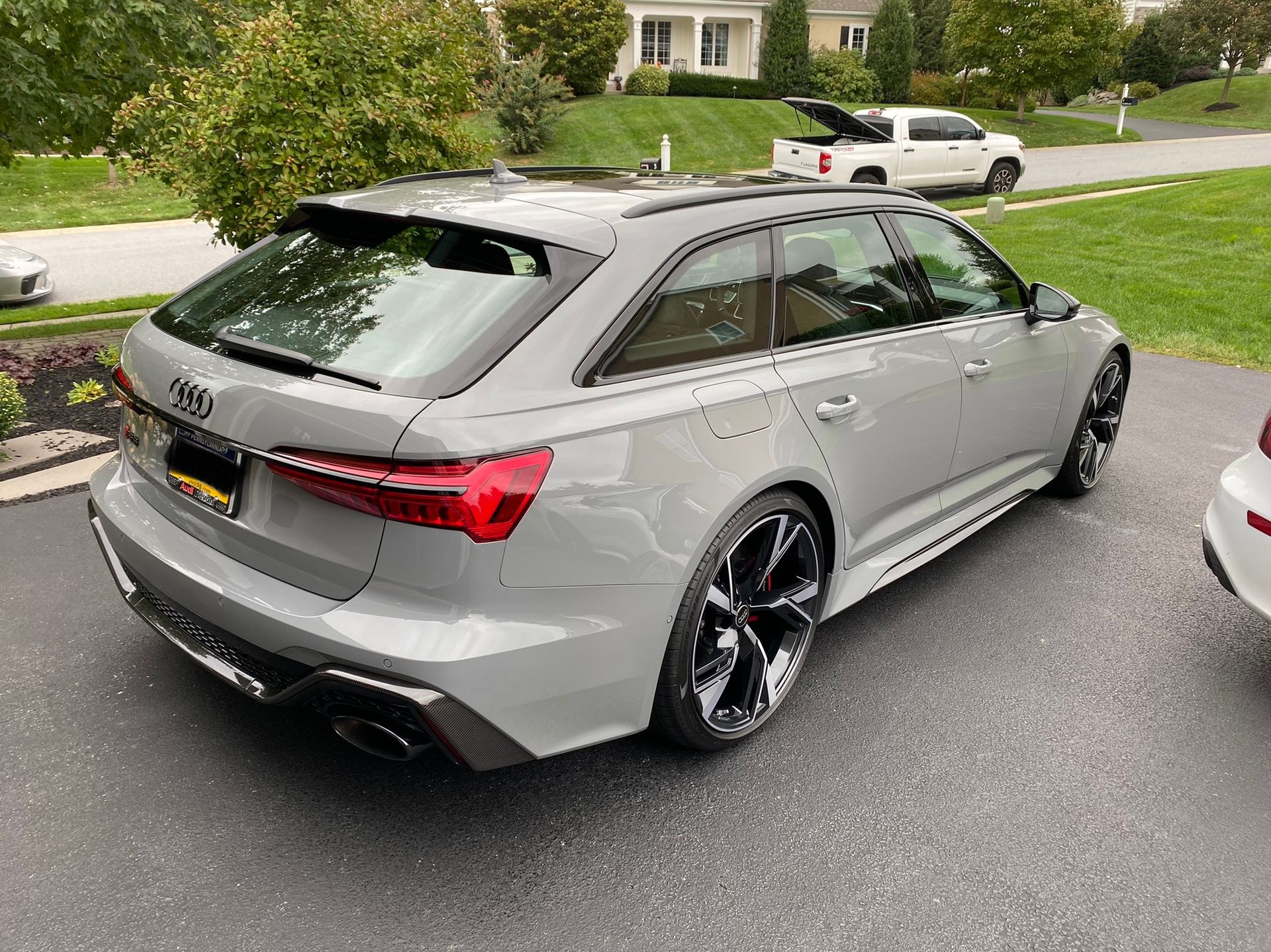 A gray audi rs6 is parked in a driveway next to a white truck.