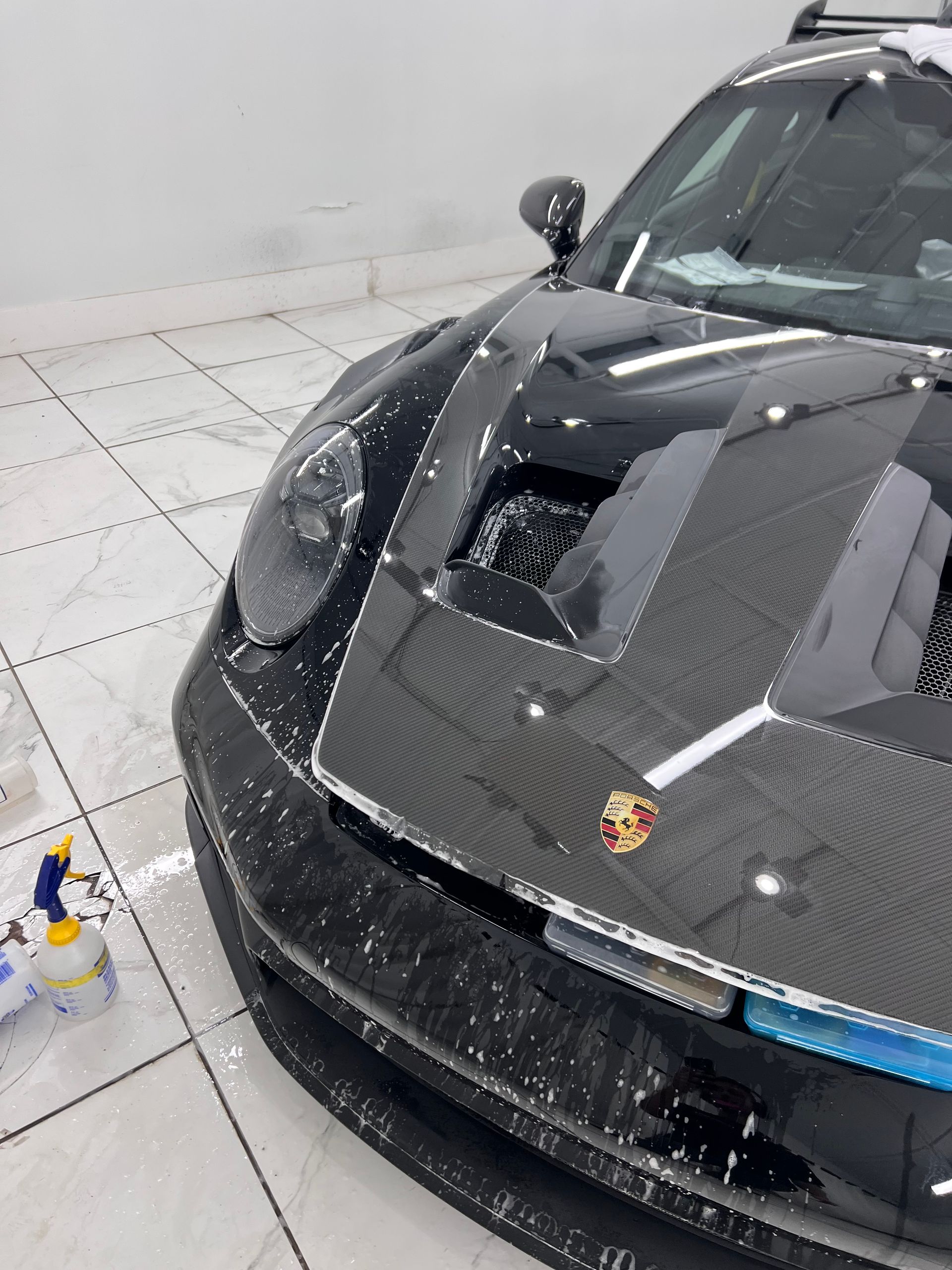 A black porsche is sitting on a tiled floor.