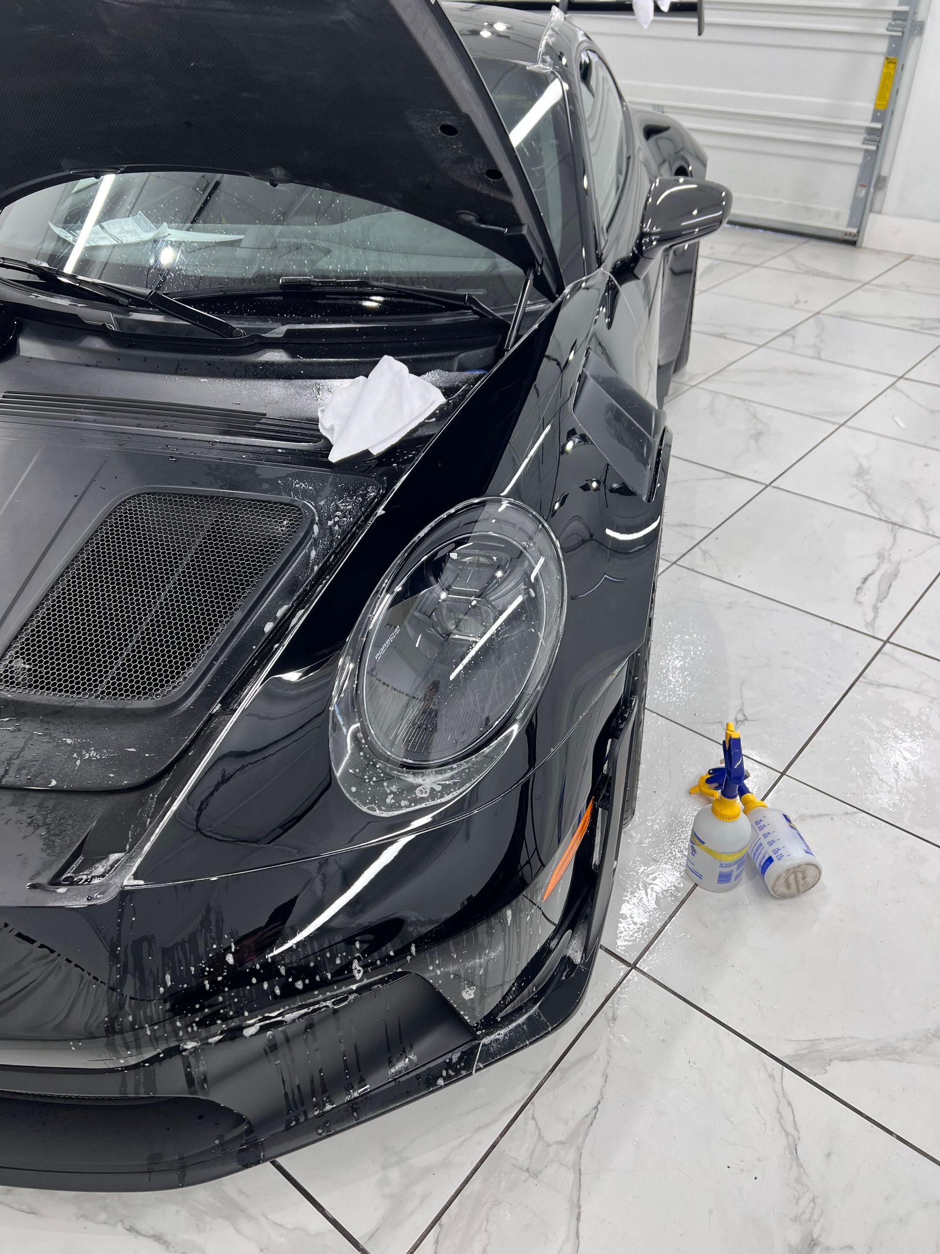 A black car with the hood up is being protective filmed.